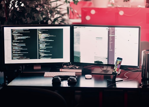 two black computer monitors on black table
