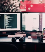 two black computer monitors on black table