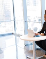 woman sits of sofa while using tablet computer